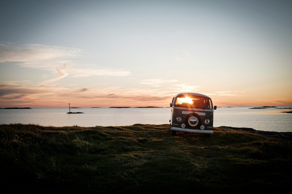 Vintage campervan parked by the ocean at sunset