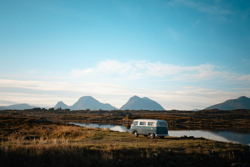 Van parked by a calm lake with mountains in Smøla, Norway